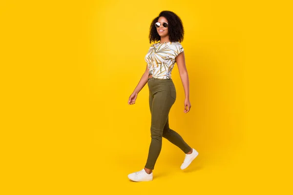 Foto samping penuh profil tubuh gadis muda afro ceria berjalan mengenakan pakaian kasual terisolasi dengan latar belakang warna kuning — Stok Foto