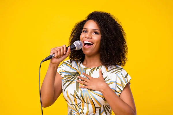 Bild av ung attraktiv afrikansk kvinna stjärna mikrofon scenen uppskattar fans reaktion isolerad över gul färg bakgrund — Stockfoto