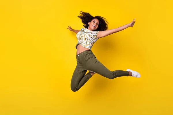 Full size foto van jong opgewonden Afrikaans meisje veel plezier jumper genieten vliegen handen vliegtuig geïsoleerd over gele kleur achtergrond — Stockfoto