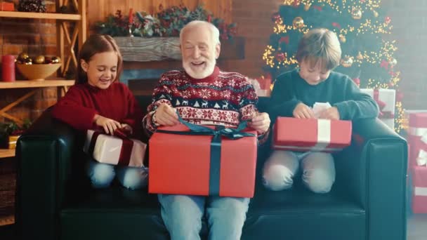 Excited crazy relatives sit comfy couch unwrapping gifts — Stock Video