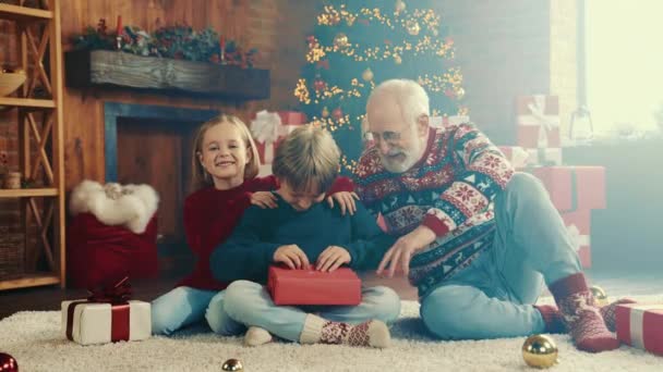 Zvědavá rodina sedět podlaha zdobené apartmán pokoj vybalování dárkové krabice — Stock video