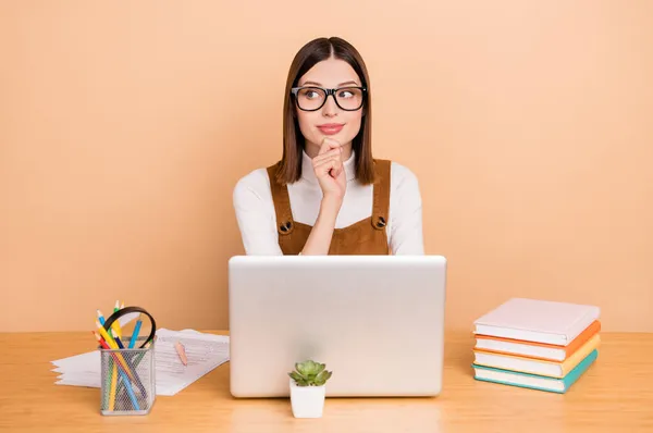 Retrato de atractiva empleada chica hábil pensativo usando portátil que arranca analizar aislado sobre fondo de color beige —  Fotos de Stock