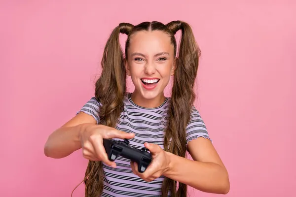Фото довольно забавной молодой женщины в полосатой футболке, играющей на игровой станции, улыбающейся изолированно розовым цветом фона — стоковое фото