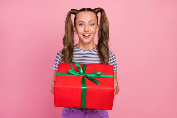 Retrato de atractiva chica de pelo largo alegre sosteniendo en las manos festal caja grande aislado sobre fondo de color rosa —  Fotos de Stock