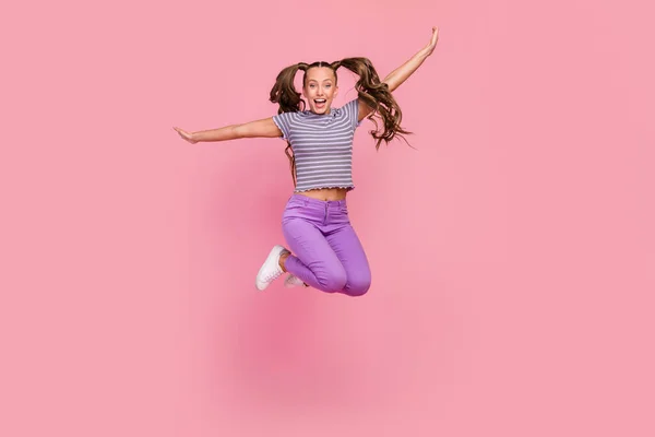 Longitud completa vista del tamaño del cuerpo de la atractiva niña alegre infantil saltando divertirse engañando aislado sobre fondo de color rosa — Foto de Stock