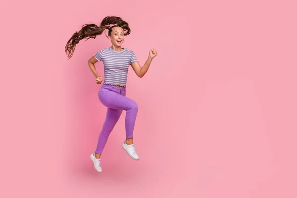 Повна довжина вигляд тіла приваблива весела тонка мотивована дівчина стрибає, бігаючи ізольовано на фоні рожевого кольору — стокове фото