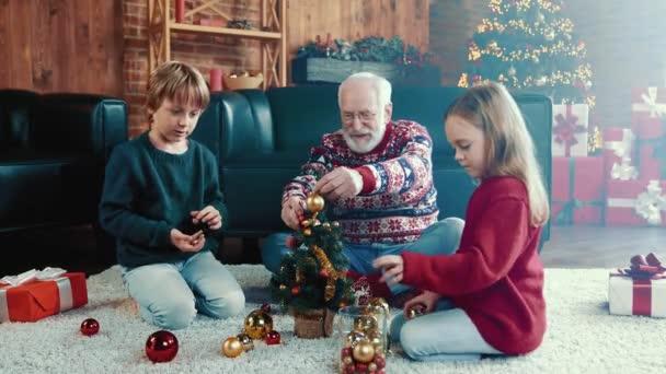 Vrolijke familieleden hangen klein speelgoed evergreen boom x-mas traditie concept — Stockvideo