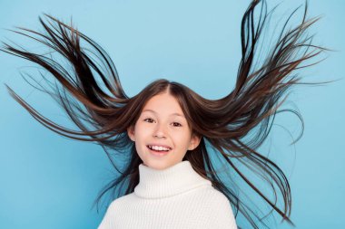 Photo of shiny pretty preteen girl dressed white pullover flying hair smiling isolated blue color background clipart