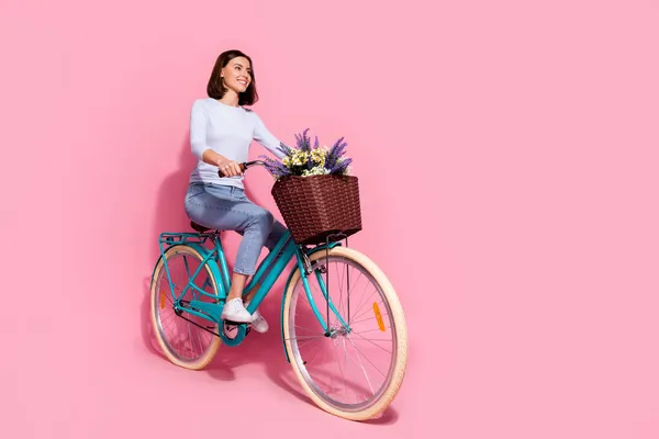 Zdjęcie marzycielski uroczy młoda kobieta nosić biały sweter jazdy rower patrząc puste miejsce uśmiechając się odizolowany różowy kolor tła — Zdjęcie stockowe