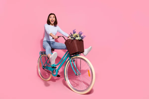 Foto de encantador despreocupado jovem mulher desgaste branco suéter condução bicicleta crescente pernas vazio espaço sorrindo isolado cor rosa fundo — Fotografia de Stock
