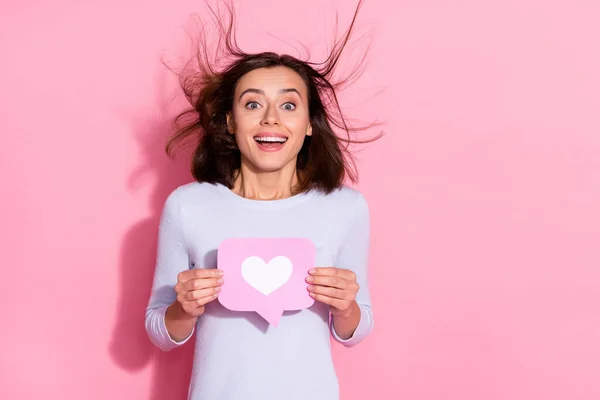 Foto de despreocupado animado jovem mulher desgaste branco suéter segurando notificação coração como sinal vazio espaço isolado cor-de-rosa fundo — Fotografia de Stock