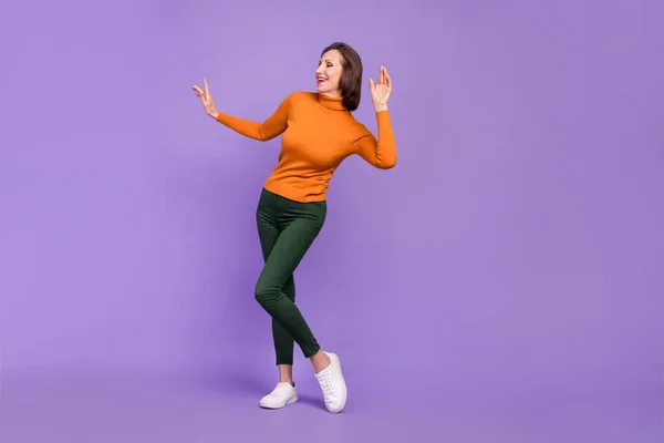 Foto de niñera engañando a mujer jubilada usar jersey naranja bailando sonriente aislado color violeta fondo —  Fotos de Stock
