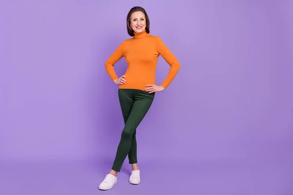 Foto de linda adorable mujer jubilada usar jersey naranja caminando sonriendo aislado color violeta fondo — Foto de Stock