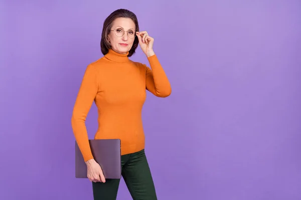 インテリジェントな女性の写真は、現代的なデバイスを保持オレンジ色のタートルネック腕の眼鏡を身に着けている空のスペース孤立紫色の背景 — ストック写真