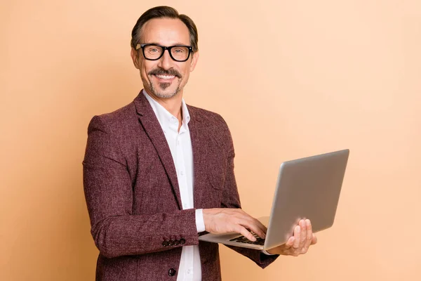 Porträtt av attraktiva glada skicklig man med bärbar dator skriva e-post förbereda rapport isolerad över beige färg bakgrund — Stockfoto