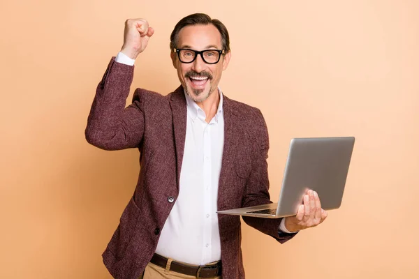 Portret van aantrekkelijke vrolijke gelukkige man met behulp van laptop verheugen met plezier grote winst geïsoleerd over beige kleur achtergrond — Stockfoto