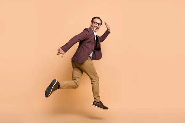 Full length body size profile side view of attractive cheery man jumping running promotion motivation isolated over beige color background — Zdjęcie stockowe