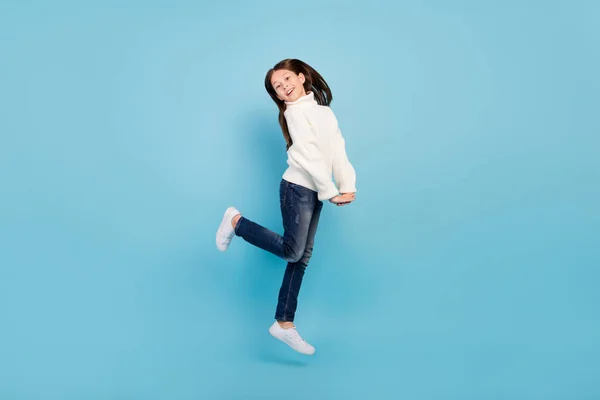 Foto de encantador estudante sonhador menina usar camisola branca sorrindo saltando alto isolado fundo de cor azul — Fotografia de Stock