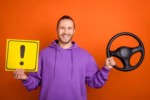 Foto van funky jonge bruine staart hairdo guy rijden auto hold teken dragen paarse sweater geïsoleerd op oranje kleur achtergrond — Stockfoto