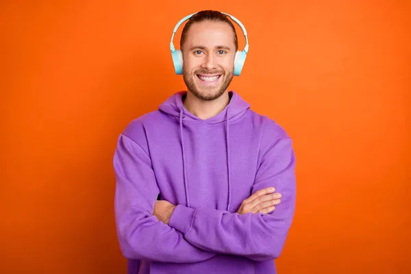 Фото крутого молодого коричневого хвоста хлопець схрестив руки слухати музику одягати фіолетовий светр ізольовано на помаранчевому кольоровому фоні — стокове фото