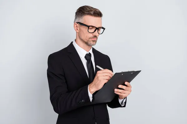 Foto av allvarliga säker ung professionell försäkringsagent bära svart jacka glasögon underteckna kontrakt isolerad grå färg bakgrund — Stockfoto