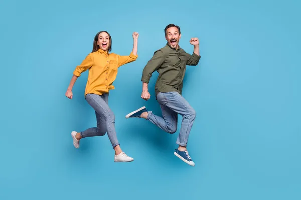 Πλήρης φωτογραφία προφίλ μέγεθος των δύο ενθουσιασμένοι άνθρωποι αυξήσει γροθιές γιορτάσουν την επιτυχία θρίαμβος απομονώνονται σε μπλε φόντο χρώμα — Φωτογραφία Αρχείου
