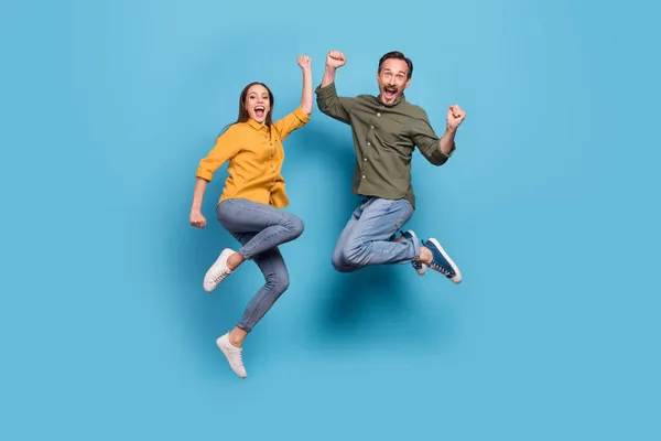 Full body foto van brunette harige echtgenoot vrouw springen tot winnaar goed humeur geïsoleerd op pastel blauw kleur achtergrond — Stockfoto