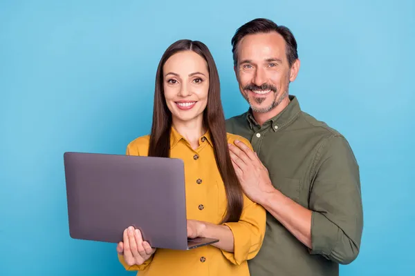 Fénykép boldog pozitív érett férfi és nő pár tartsa kezét számítógép elszigetelt kék színű háttér — Stock Fotó