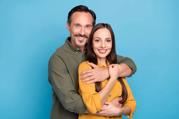 Foto de duas pessoas positivas sinceras homem abraço senhora por trás do sorriso dos dentes olhar câmera isolada no fundo de cor azul — Fotografia de Stock