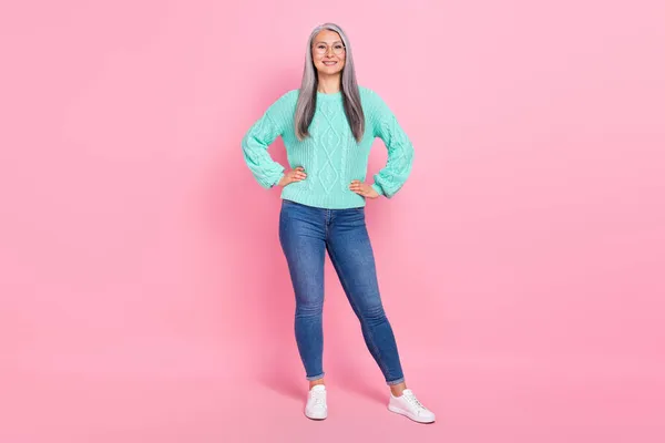 Foto de tamaño completo de lindo peinado gris de señora de edad stand desgaste gafas suéter jeans zapatos aislados en el fondo de color rosa —  Fotos de Stock