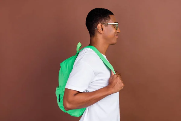 Foto del lado del perfil de un joven afro que sostiene los cursos de aprendizaje en bolsa parecen espacios vacíos aislados sobre fondo de color marrón —  Fotos de Stock