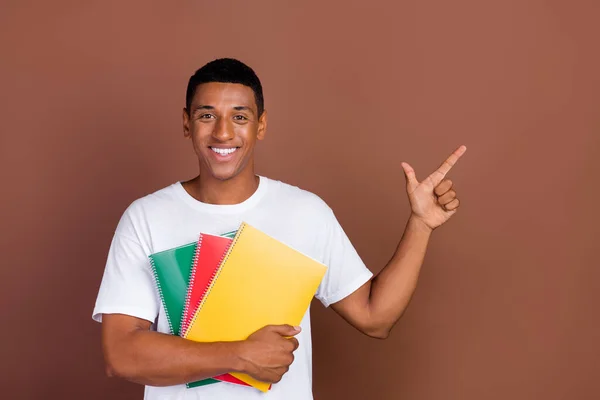 Foto van jonge afro man houden notebook geven vinger lege ruimte kiezen raden aan te suggereren geïsoleerd over bruine kleur achtergrond — Stockfoto