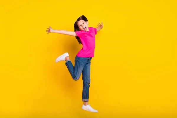 Foto van verbaasd meisje springen run bewegen open mond dragen roze t-shirt jeans schoenen geïsoleerde gele kleur achtergrond — Stockfoto