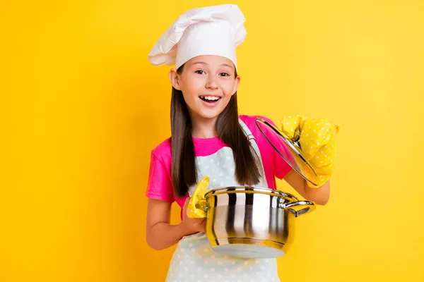 Zdjęcie podekscytowany szef kuchni dziewczyna otwarta rondel sprawdzić posiłek gotowy nosić biały fartuch kapelusz odizolowany żółty kolor tło — Zdjęcie stockowe
