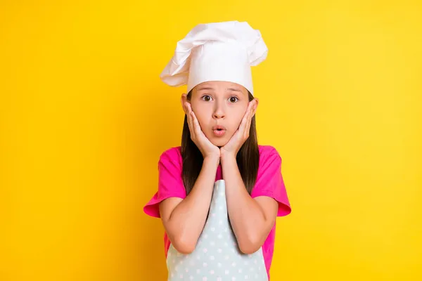 Photo of crazy speechless stunned girl hands cheeks open mouth wear white apron hat isolated yellow color background