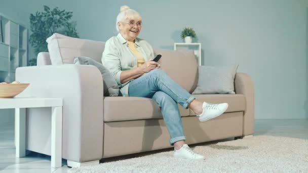 Funny abuela sentarse sofá disfrutar de la comedia película interruptor de canal de control remoto — Vídeos de Stock