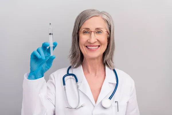 Фото щасливої веселої зрілої леді-лікар в білому пальто видовищ посміхається готовий робити вакцинацію ізольований сірий колір фону — стокове фото