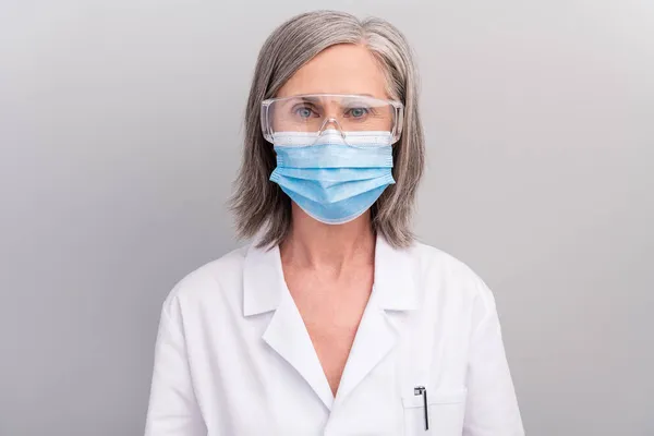 Φωτογραφία από αυτοπεποίθηση όμορφη ηλικιωμένη γυναίκα doc ντυμένος λευκό ομοιόμορφο γυαλιά μάσκα προσώπου απομονωμένο γκρι φόντο χρώμα — Φωτογραφία Αρχείου