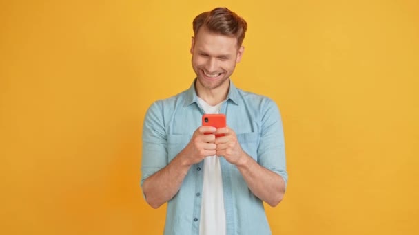 Positivo bello curioso ragazzo intelligente tenere il telefono digitando flirty messaggio emozionante — Video Stock