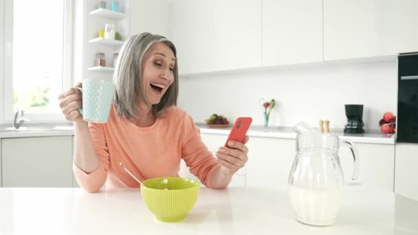 Positivo alegre abuela blogging chat teléfono disfrutar de capuchino — Vídeo de stock