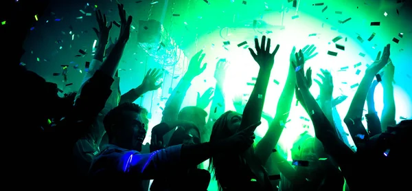 Foto av bekymmerslösa ungkarlar grabbar njuta glädje ljud show disco golv höja händerna under färgglada futuristiska ljus flyger konfetti — Stockfoto
