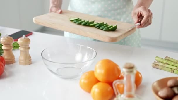 Alte Dame schneidet Gurke in Scheiben und fügt Salatschüssel hinzu — Stockvideo