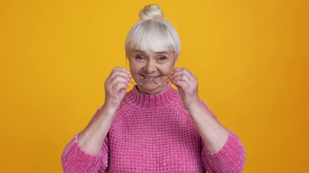 Positieve gezonde gepensioneerde oma gezet op bril look spiegel concept — Stockvideo