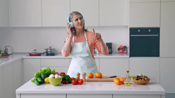 Insouciante joyeuse grand-mère cuisinier repas écouter écouteurs musique motivation — Video