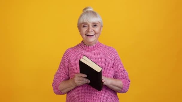 Pozytywne ładne marzycielski starsza pani czytać książki cieszyć się przytulić marzenie wygląd puste miejsce — Wideo stockowe