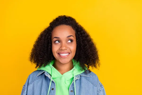 Foto de soñadora linda mujer africana vestida jeans camisa buscando espacio vacío sonriendo aislado color amarillo fondo — Foto de Stock