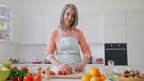 Positiv selbstbewusste Köchin schneidet Scheibe Kirschtomate — Stockvideo