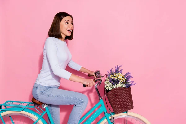 Foto de chocado impressionado jovem mulher usar camisola branca olhando espaço vazio equitação bicicleta sorrindo isolado cor de fundo rosa — Fotografia de Stock