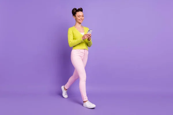 Foto lateral de perfil de tamaño completo de la joven chica sonriente atractiva ir a pie de navegación en el teléfono inteligente aislado en el fondo de color púrpura — Foto de Stock