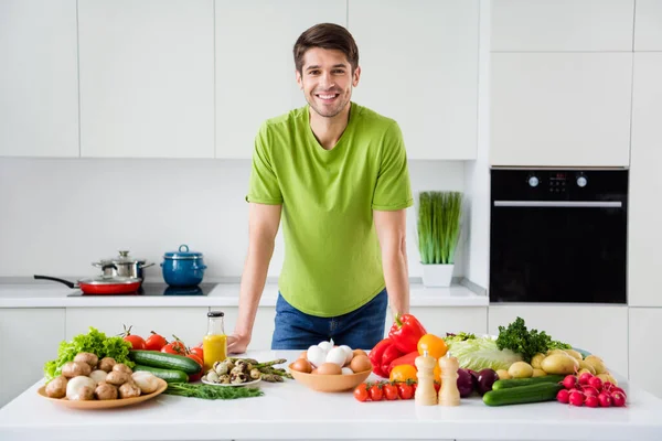 Фотопортрет молодого чоловіка, який готує овочі салат посміхається на кухні — стокове фото